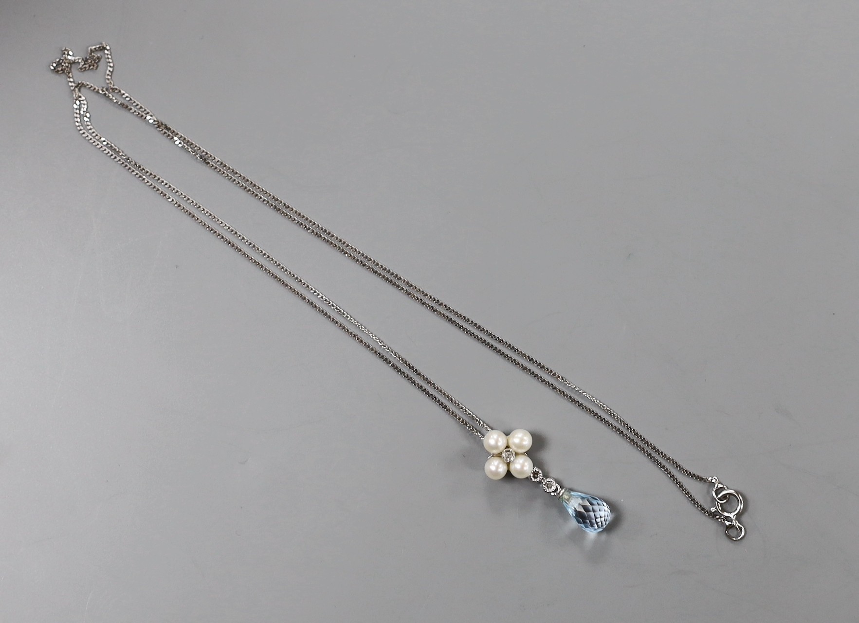 A modern 9k white metal, blue topaz, cultured pearl and diamond cluster set drop pendant, 23mm, on a 375 fine link chain, 46cm, gross weight 2.2 grams.